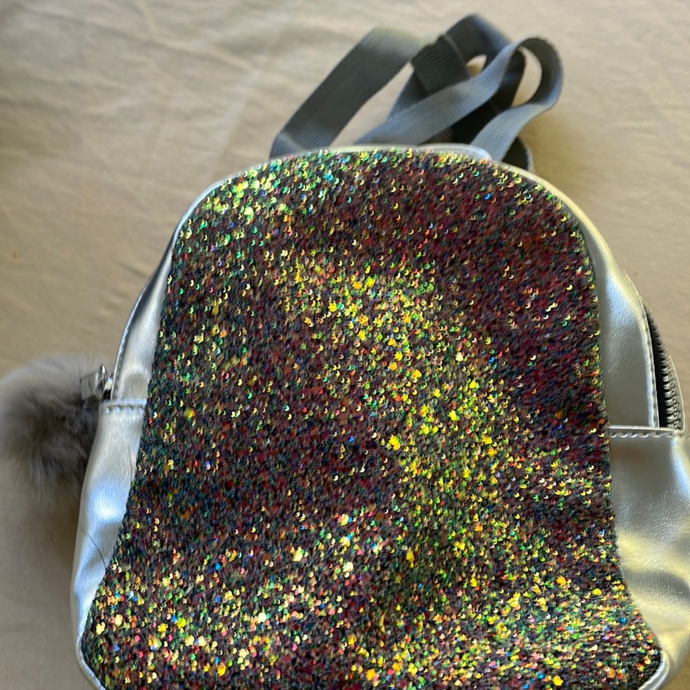 Silver sparkly backpack with adjustable straps and fur pom pom on zipper